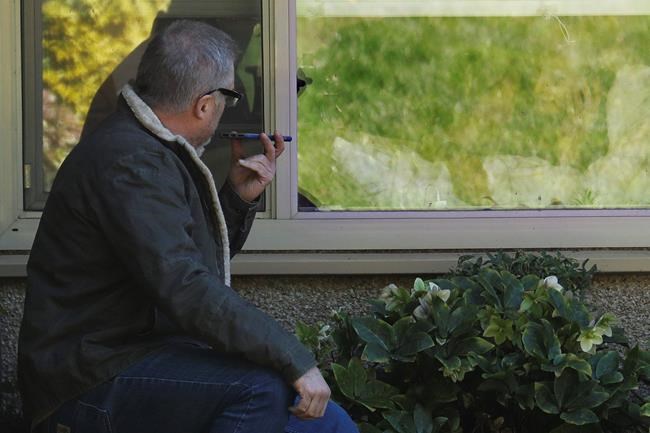 Marty Shape, left, talks to his mother, Judy Shape, right, on the phone as they look at each other through her window, Monday, March 9, 2020, at the Life Care Center in Kirkland, Wash., near Seattle. In-person visits at the facility are not allowed, as the nursing home is at the center of the outbreak of the coronavirus in Washington state. (AP Photo/Ted S. Warren)