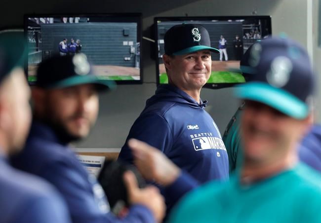 FILE - In this April 12, 2019 file photo, Seattle Mariners manager Scott Servais, center, smiles in the dugout before a baseball game against the Houston Astros in Seattle. Spring training for the Mariners ahead of the 2020 season will feature young players and prospects that could be at the heart of whether the Mariners' rebuild plans ultimately work. (AP Photo/Ted S. Warren, File)