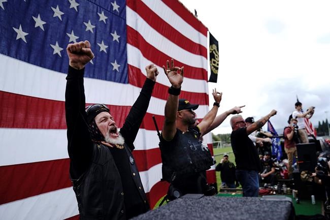FILE - Members of the Proud Boys cheer on stage as they and other right-wing demonstrators rally, Saturday, Sept. 26, 2020, in Portland, Ore. President Donald Trump didn't condemn white supremacist groups and their role in violence in some American cities this summer. Instead, he said the violence is a “left-wing