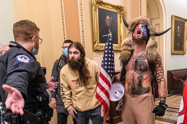 FILE - In this Wednesday, Jan. 6, 2021 file photo, supporters of President Donald Trump, including Jacob Chansley, right with fur hat, are confronted by U.S. Capitol Police officers outside the Senate Chamber inside the Capitol in Washington. Congress is set to hear from former security officials about what went wrong at the U.S. Capitol on Jan. 6. That's when when a violent mob laid siege to the Capitol and interrupted the counting of electoral votes. Three of the four testifying Tuesday resigned under pressure immediately after the attack, including the former head of the Capitol Police. (AP Photo/Manuel Balce Ceneta, File)