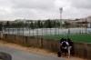 Italian journalists look through a gap in the fence trying to watch a closed training session of the Atalanta soccer team at the Pina Manique stadium in Lisbon, Tuesday Aug. 11, 2020. Atalanta will face PSG in a Champions League quarterfinals match on Wednesday in Lisbon. (AP Photo/Armando Franca)