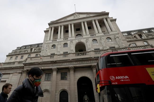 Pedestrians wearing face masks walk past the Bank of England in London, Wednesday, March 11, 2020. Britain's Chancellor of the Exchequer Rishi Sunak will announce the first budget since Britain left the European Union. (AP Photo/Matt Dunham)