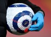 A member of the ground staff carries a ball wearing plastic gloves against the coronavirus ahead of the English Premier League soccer match between Liverpool and Everton at Anfield in Liverpool, England, Saturday, Feb. 20, 2021. (Lawrence Griffiths/ Pool via AP)