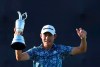 United States' Collin Morikawa holds up the claret jug trophy as he poses for photographers on the 18th green after winning the British Open Golf Championship at Royal St George's golf course Sandwich, England, Sunday, July 18, 2021. (AP Photo/Ian Walton)