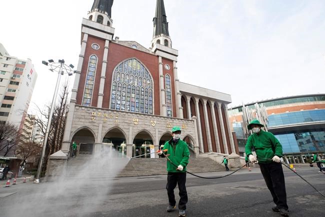 Workers wearing face masks spray disinfectant as a precaution against the new coronavirus in front of Myungsung Church in Seoul, South Korea, Wednesday, Feb. 26, 2020. The number of new virus infections in South Korea jumped again Wednesday and the U.S. military reported its first case among its soldiers based in the Asian country, with his case and many others connected to a southeastern city with an illness cluster. (Yun Dong-jin/Yonhap via AP)