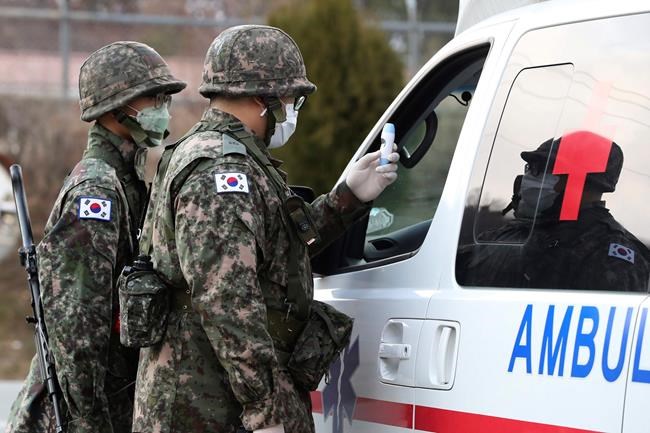 South Korean army soldiers wearing face masks check the temperature of a driver at a checkpoint of a military base in Daegu, South Korea, Wednesday, Feb. 26, 2020. The number of new virus infections in South Korea jumped again Wednesday and the U.S. military reported its first case among its soldiers based in the Asian country, with his case and many others connected to a southeastern city with an illness cluster. (Ryu Hyung-seok/Yonhap via AP)