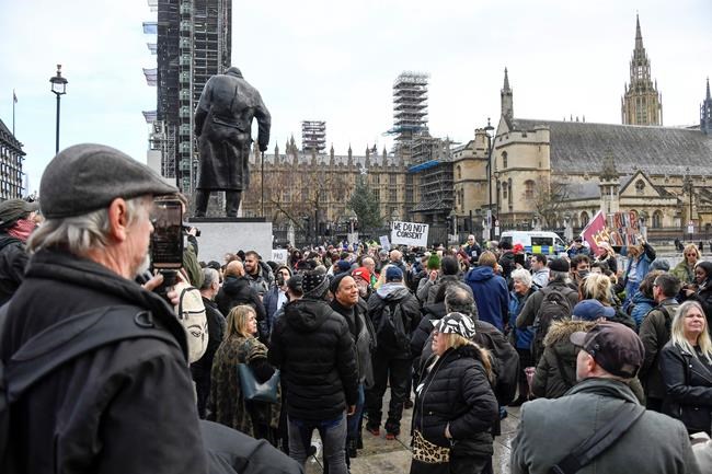 People attend an anti-lockdown demonstration in Parliament Square, in London, Monday, Dec. 14, 2020. Britain launched its vaccination program this month after becoming the first country to give emergency approval to the Pfizer-BioNtech vaccine, and authorities plan to dispense 800,000 doses in the first phase. (AP Photo/Alberto Pezzali)