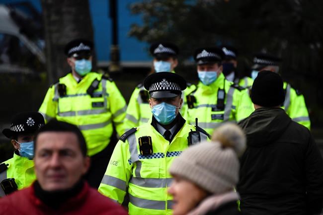 Police officers wear face masks as they patrol an anti-lockdown demonstration in Parliament Square, in London, Monday, Dec. 14, 2020. Britain launched its vaccination program this month after becoming the first country to give emergency approval to the Pfizer-BioNtech vaccine, and authorities plan to dispense 800,000 doses in the first phase. (AP Photo/Alberto Pezzali)