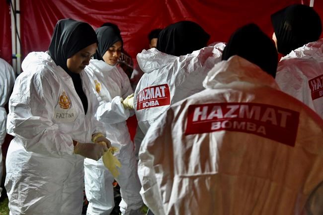 In this photo released by Malaysia's Ministry of Health, health workers put on full protective suits as they prepare for the arrival of evacuated Malaysian from China's Wuhan, the epicenter of the new coronavirus outbreak, at Kuala Lumpur International Airport in Sepang, Malaysia, Wednesday, Feb. 26, 2020. U.S. health officials warned Tuesday that the burgeoning coronavirus is certain to spread more widely in the country at some point, even as their counterparts in Europe and Asia scrambled to contain new outbreaks of the illness. (Muzzafar Kasim/Malaysia's Ministry of Health via AP)