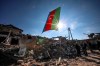 Azerbaijan's national flag flies over destroyed houses in a residential area that was hit by rocket fire overnight by Armenian forces, on Thursday, Oct. 22, 2020 in Ganja, Azerbaijan's second largest city, near the border with Armenia. Heavy fighting over Nagorno-Karabakh is continuing with Armenia and Azerbaijan trading blame for new attacks. The nearly four weeks of hostilities have raised the threat of Turkey and Russia being drawn into the conflict. (AP Photo/Aziz Karimov)