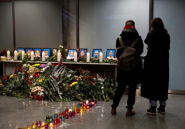 Two women mourn standing in front of a memorial for the flight crew of the Ukrainian 737-800 plane that crashed on the outskirts of Tehran, inside Borispil international airport outside Kyiv, Ukraine, late Wednesday, Jan. 8, 2020. A Ukrainian airplane carrying 176 people crashed on Wednesday shortly after takeoff from Tehran's main airport, killing all onboard, Iranian state TV and officials in Ukraine said. (AP Photo/Efrem Lukatsky)