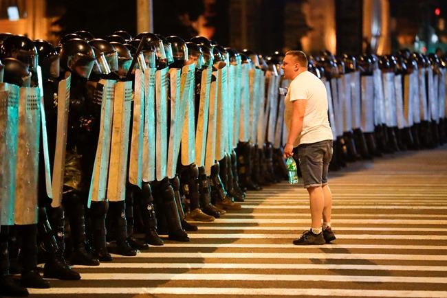 A protester speaks to police as they block the road during a rally after the Belarusian presidential election in Minsk, Belarus, Sunday, Aug. 9, 2020. Police and protesters clashed in Belarus' capital and the major city of Brest on Sunday after the presidential election in which the authoritarian leader who has ruled for a quarter-century sought a sixth term in office. (AP Photo/Sergei Grits)