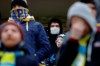 In this photo taken on Thursday, March 19, 2020, football fans of FC Bate, one of them wearing a face mask, watch the Belarus Championship soccer match between Energetik-BGU and Bate in Minsk, Belarus. Longtime Belarus President Alexander Lukashenko is proudly keeping soccer and hockey arenas open even though most sports around the world have shut down because of the coronavirus pandemic. The new coronavirus causes mild or moderate symptoms for most people, but for some, especially older adults and people with existing health problems, it can cause more severe illness or death. (AP Photo/Sergei Grits)