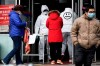 A worker in overalls screen for fever at the entrance to a supermarket in Beijing Thursday, Feb. 27, 2020. South Korea and China each reported hundreds more virus cases Thursday as the new illness persists in the worst-hit areas and spreads beyond borders. (AP Photo/Ng Han Guan)