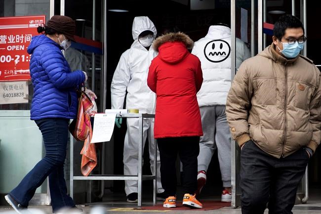 A worker in overalls screen for fever at the entrance to a supermarket in Beijing Thursday, Feb. 27, 2020. South Korea and China each reported hundreds more virus cases Thursday as the new illness persists in the worst-hit areas and spreads beyond borders. (AP Photo/Ng Han Guan)