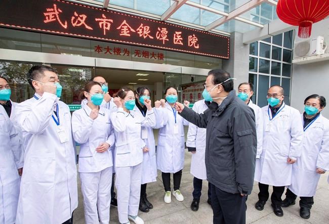 In this photo released by China's Xinhua News Agency, Chinese Premier Li Keqiang, center, speaks with medical workers at Wuhan Jinyintan Hospital in Wuhan in central China's Hubei province, Monday, Jan. 27, 2020. China on Monday expanded its sweeping efforts to contain a deadly virus, extending the Lunar New Year holiday to keep the public at home and avoid spreading infection. (Li Tao/Xinhua via AP)