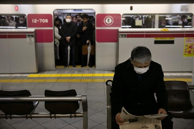 A commuter wearing a mask reads a newspaper while waiting for a train to arrive during morning rush hours Tuesday, Jan. 28, 2020, in Tokyo. China on Tuesday reported 25 more deaths from a new viral disease as the U.S. government prepared to evacuate Americans from the city at the center of the outbreak. Japan, Mongolia, France and other governments also were preparing evacuations. (AP Photo/Jae C. Hong)