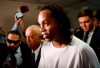 Former soccer star Ronaldinho is escorted by police to go before Judge Mirko Valinotti at the Justice Palace court in Asuncion, Paraguay, Friday, March 6, 2020. Ronaldinho has been detained by Paraguayan police for allegedly entering the country with a falsified passport. (AP Photo/Jorge Saenz)