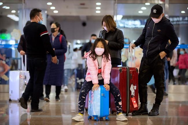 Travelers wear a face masks as they stand in the arrivals area at Beijing Capital International Airport in Beijing, Thursday, Jan. 23, 2020. China closed off a city of more than 11 million people Thursday, halting transportation and warning against public gatherings, to try to stop the spread of a deadly new virus that has sickened hundreds and spread to other cities and countries in the Lunar New Year travel rush. (AP Photo/Mark Schiefelbein)