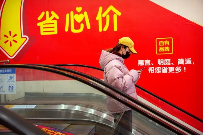 A woman wears a face mask as she rides an escalator at a supermarket in Beijing, Tuesday, Jan. 28, 2020. China's death toll from a new viral disease that is causing mounting global concern rose by 25 to at least 106 on Tuesday as the United States and other governments prepared to fly their citizens out of the locked-down city at center of the outbreak. (AP Photo/Mark Schiefelbein)