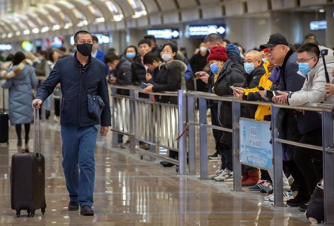 A traveler wearing a face mask walks into the arrivals area at Beijing Capital International Airport in Beijing, Thursday, Jan. 23, 2020. China closed off a city of more than 11 million people Thursday, halting transportation and warning against public gatherings, to try to stop the spread of a deadly new virus that has sickened hundreds and spread to other cities and countries in the Lunar New Year travel rush. (AP Photo/Mark Schiefelbein)