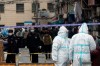 Police officers and workers in protective suits close off a neighborhood as it is placed under lockdown in Shanghai, China, Thursday, Jan. 21, 2021. Shanghai has imposed lockdowns on two of China's best-known hospitals and some surrounding residential communities after they were linked to new coronavirus cases. (Chinatopix via AP)