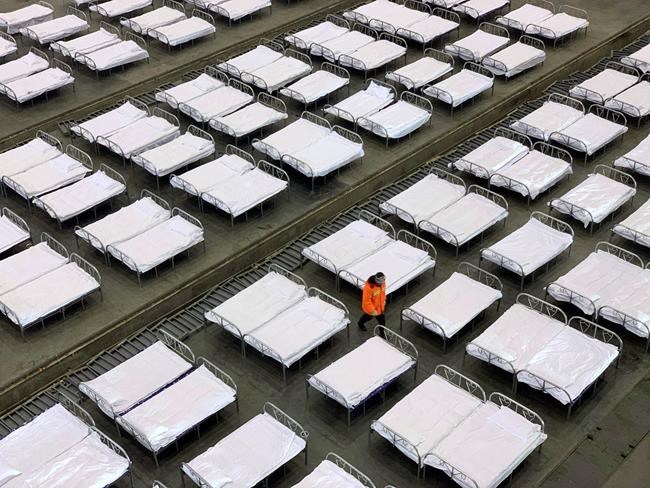 Workers arrange beds in a convention center that has been converted into a temporary hospital in Wuhan in central China's Hubei Province, Tuesday, Feb. 4, 2020. China said Tuesday the number of infections from a new virus surpassed 20,000 as medical workers and patients arrived at a new hospital and President Xi Jinping said