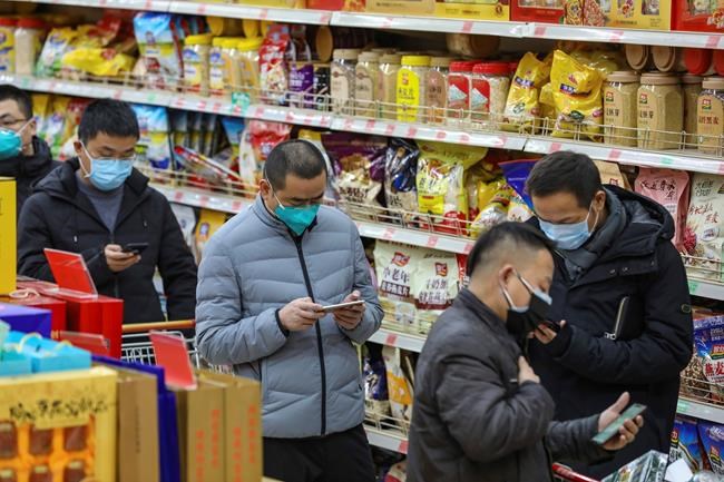 Shoppers wearing face masks wait to pay for their groceries at a supermarket in Wuhan in central China's Hubei province, Saturday, Jan. 25, 2020. The virus-hit Chinese city of Wuhan, already on lockdown, banned most vehicle use downtown and Hong Kong said it would close schools for two weeks as authorities scrambled Saturday to stop the spread of an illness that is known to have infected more than 1,200 people and killed 41, according to officials. (Chinatopix via AP)