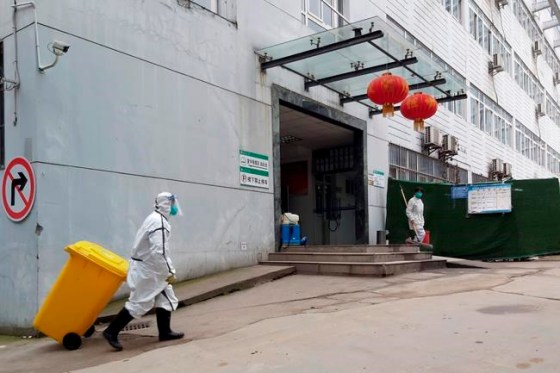In this Thursday, Jan. 23, 2020, photo, a staff member wearing a hazardous materials suit hauls a bin at a hospital that reported a coronavirus death in Yichang in central China's Hubei Province. China is swiftly building a 1,000-bed hospital dedicated to patients infected with a new virus that has killed 26 people, sickened hundreds and prompted unprecedented lockdowns of cities during the country's most important holiday. (Chinatopix via AP)