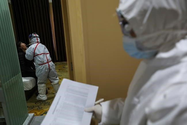A medical worker in a protective suit collects a sample for nucleic acid tests from a suspected virus patient at a hotel being used to place people in medical isolation in Wuhan in central China's Hubei Province, Tuesday, Feb. 4, 2020. Hong Kong hospitals cut services as thousands of medical workers went on strike for a second day Tuesday to demand the border with mainland China be shut completely, as a new virus caused its first death in the semi-autonomous territory and authorities feared it was spreading locally. (Chinatopix via AP)