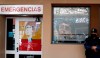A police officer stands outside the hospital where Diego Maradona is hospitalized and where images of him placed by fans are reflected in the windows, in La Plata, Argentina Tuesday, Nov. 3, 2020. Maradona was admitted to the hospital with signs of depression Monday, three days after his 60th birthday. (AP Photo/ Natacha Pisarenko)