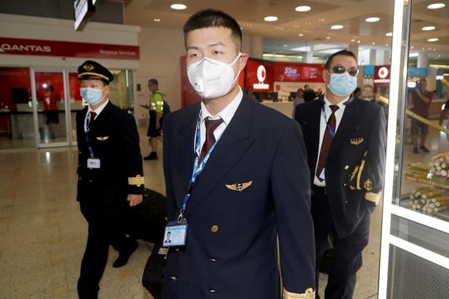 Flight crew from China Eastern Airlines leave the airport wearing face masks after arriving in Sydney Thursday, Jan. 23, 2020, from a flight from Wuhan, China. China closed off a city of more than 11 million people as part of a radical effort to prevent the spread of a deadly virus that has sickened more than 500 people and has begun to spread to other cities and countries in the region. (AP Photo/Rick Rycroft)