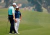 South Africa's Ernie Els, left, sprays water from a bottle as he and South Korea's K.J. Choi chat while waiting to hit on the 6th hole during the opening round of the Australian Open golf tournament in Sydney, Thursday, Dec. 5, 2019. (AP Photo/Rick Rycroft)