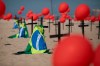 Crosses, red balloons and Brazilian nation flags are placed in the sand on Copacabana beach in a demonstration organized by Rio de Paz to honor the victims of COVID-19, as the country heads to a milestone of 100,000 new coronavirus related deaths, in Rio de Janeiro, Brazil, Saturday, Aug. 8, 2020. (AP Photo/Mario Lobao)