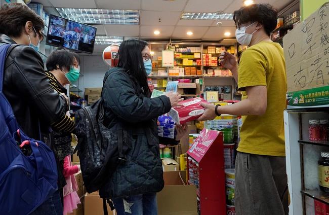 People wearing face masks queue up to purchase tissue papers at a pharmacy in Hong Kong, Thursday, Feb. 6, 2020. Ten more people were sickened with a new virus aboard one of two quarantined cruise ships with some 5,400 passengers and crew aboard, health officials in Japan said Thursday, as China reported 73 more deaths and announced that the first group of patients were expected to start taking a new antiviral drug. (AP Photo/Vincent Yu)