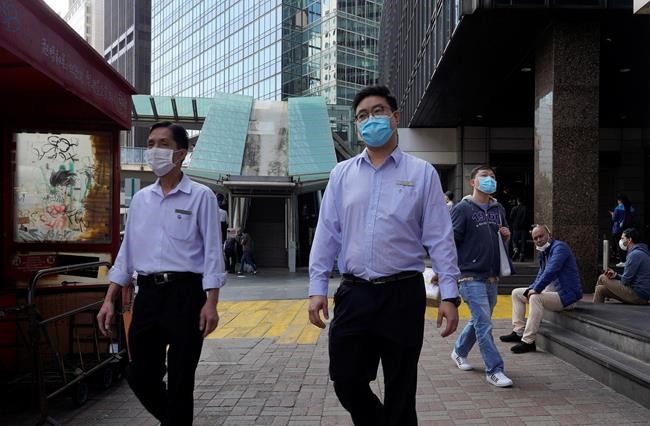 People wearing face masks walk on a street in Hong Kong Tuesday, Feb. 25, 2020. China and South Korea on Tuesday reported more cases of a new viral illness that has been concentrated in North Asia but is causing global worry as clusters grow in the Middle East and Europe. (AP Photo/Vincent Yu)