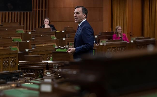 With a limited number of Members of Parliament on hand and spread out, Minister of Finance Bill Morneau responds to a question after tabling the governments COVID19 financial measures bill in the House of Commons Wednesday March 25, 2020 in Ottawa. THE CANADIAN PRESS/Adrian Wyld