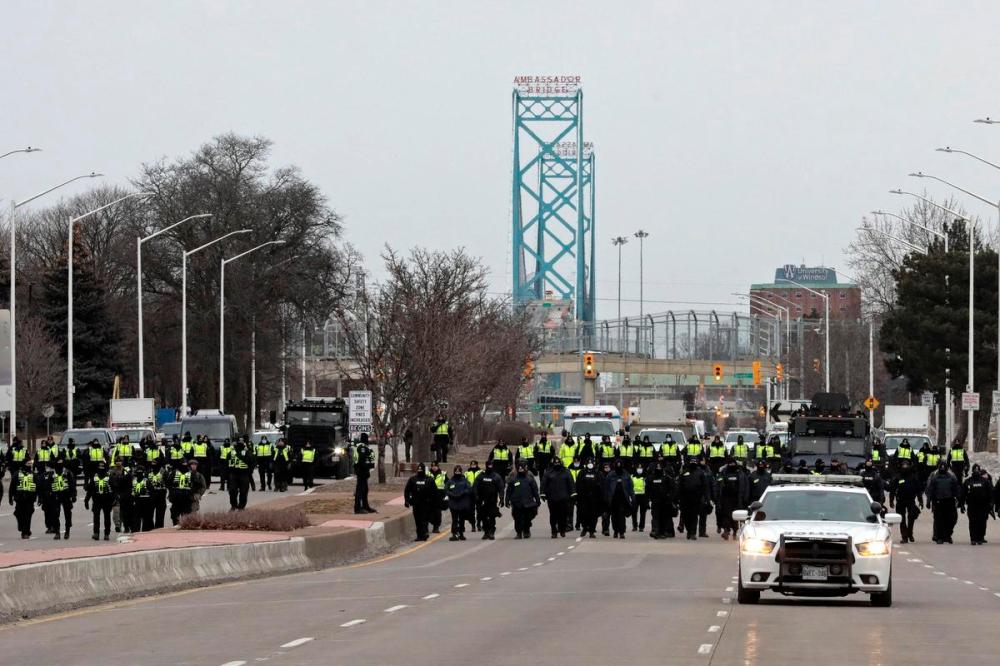 JEFF KOWALSKY - AFP via GETTY IMAGES
Police gather on Feb. 13, 2022 to clear protestors against COVID-19 vaccine mandates who blocked the entrance to the Ambassador Bridge in Windsor.