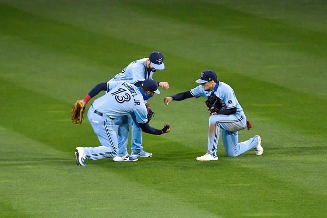 Toronto Blue Jays left fielder Lourdes Gurriel Jr., left, center fielder Randal Grichuk, top, and right fielder Cavan Biggio celebrate their win over the New York Yankees in a baseball game in Buffalo, N.Y., Monday, Sept. 7, 2020. (AP Photo/Adrian Kraus)