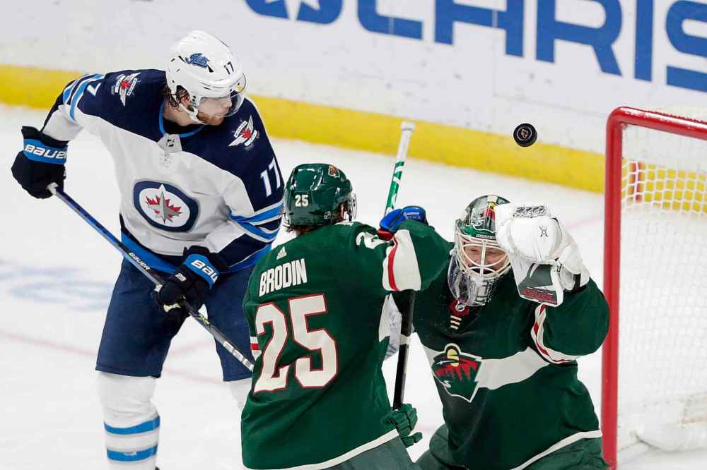 Minnesota Wild goalie Devan Dubnyk defects a puck with Winnipeg Jets center Adam Lowry (17) and Minnesota Wild defenseman Jonas Brodin (25) watching in the third period. (Andy Clayton-King / The Associated Press)