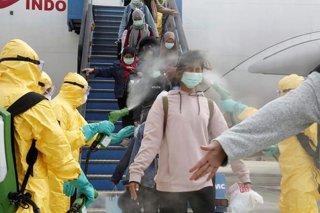 In this photo released by the Indonesian Foreign Ministry, Indonesians who arrived from Wuhan, China, are sprayed with antiseptic at Hang Nadim Airport in Batam, Indonesia Sunday, Feb. 2, 2020. Indonesians evacuated from Wuhan, the Chinese city at the center of a deadly virus outbreak, were transported to a quarantine zone on a remote island at the edge of the South China Sea, shortly after landing on Batam, an island near Singapore on Sunday morning. (Indonesian Foreign Ministry via AP)