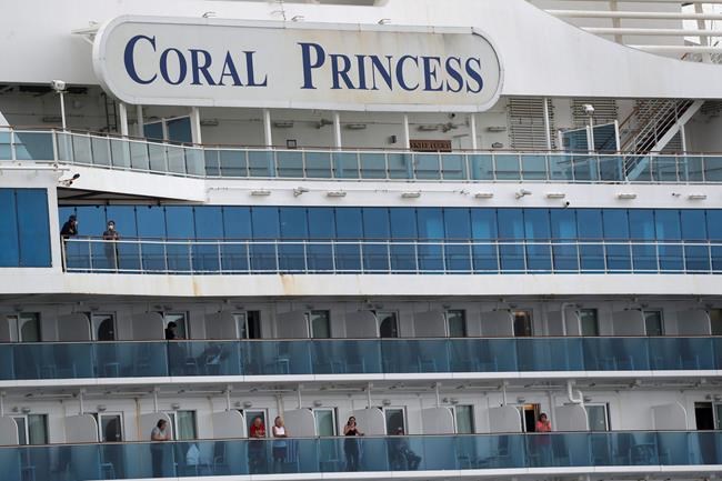 Passengers look out from the Coral Princess cruise ship while docked in Miami, Monday, April 6, 2020. Authorities say 14 people have been taken to hospitals from the cruise ship that docked in Florida with coronavirus victims aboard and one of them has died at a hospital. Two fatalities were reported earlier aboard the Coral Princess. The Coral Princess had more than 1,000 passengers and nearly 900 crew members. It began disembarking fit passengers Sunday. Any with symptoms of COVID-19 or recovering were being kept on ship until medically cleared. (AP Photo/Wilfredo Lee)