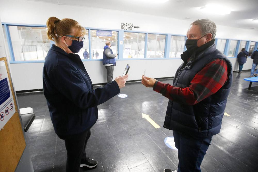 JOHN WOODS / WINNIPEG FREE PRESS
Trish Buhler, hockey mum and manager of St Boniface Seals, scans the vaccination card of Shaun Chornley as he enters the Bertrand Arena.