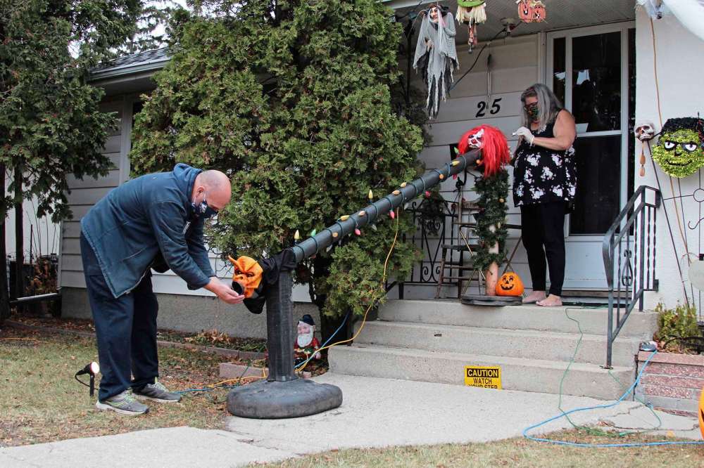 Jim (left) and Kim Lane constructed a COVID-friendly candy chute to slide candy to trick-or-treaters on Halloween. (Sydney Hildebrandt / Winnipeg Free Press)