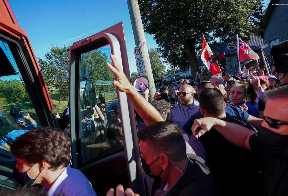 Nathan Denette - THE CANADIAN PRESS
Liberal Leader Justin Trudeau’s RCMP security detail put their hands up to protect him as protesters shout and through gravel while leaving a campaign stop in London Ont., on Monday.