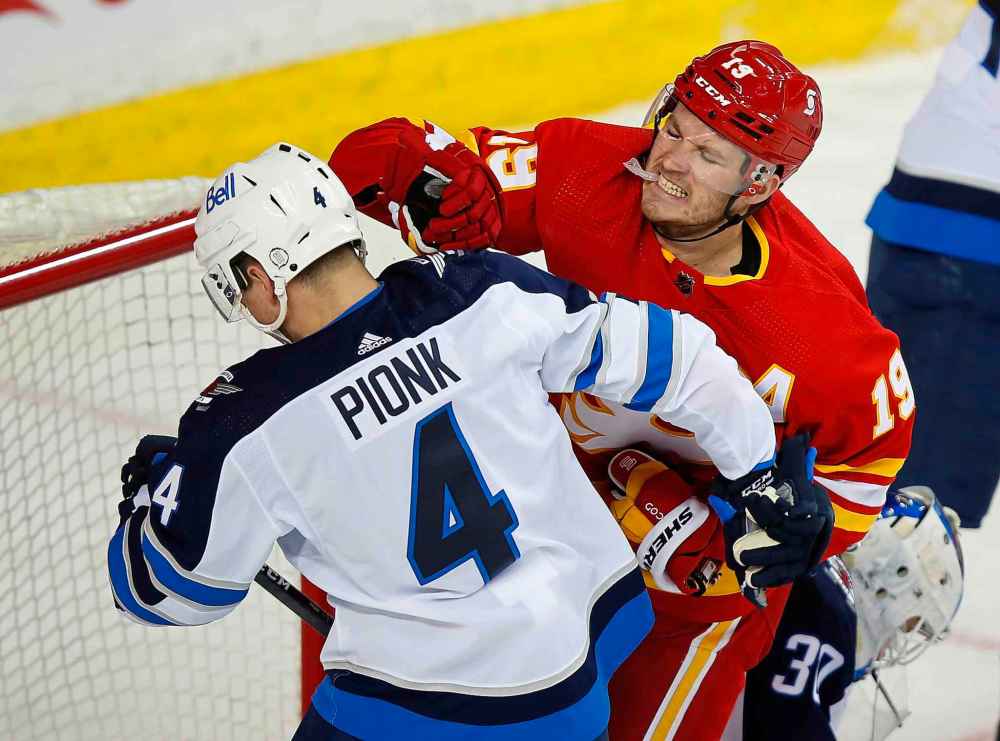 CP
Winnipeg Jets' Neal Pionk and Calgary Flames' Matthew Tkachuk exchange blows in front of the Jet's net during the first period. (Todd Korol / The Canadian Press)
