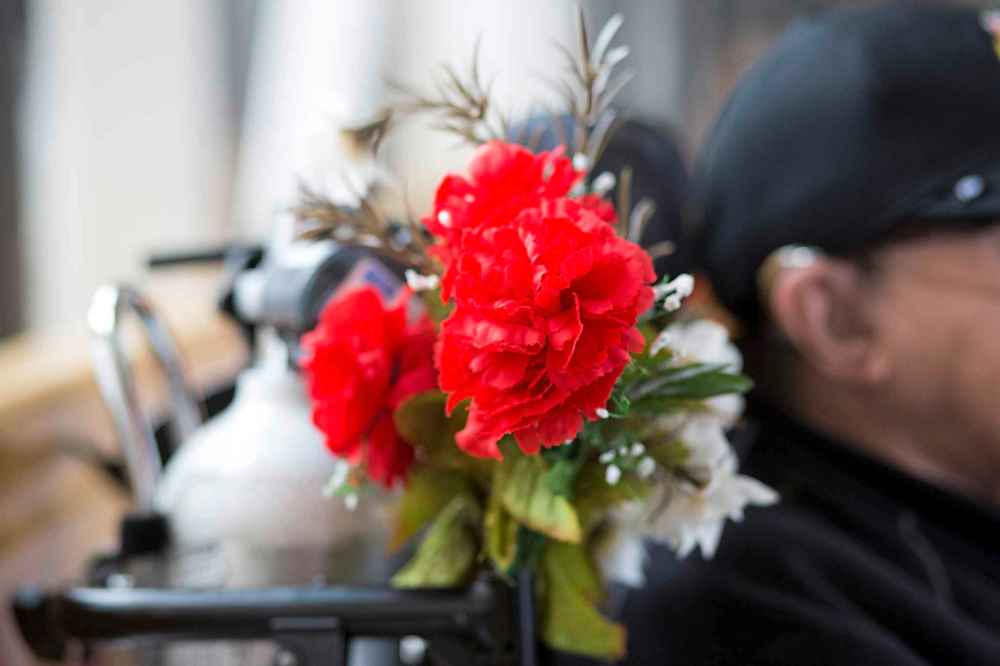 A whimsical spray of vibrant plastic flowers is attached to the wheelchair beside Yaramenko's head. (Mikaela MacKenzie / Winnipeg Free Press)