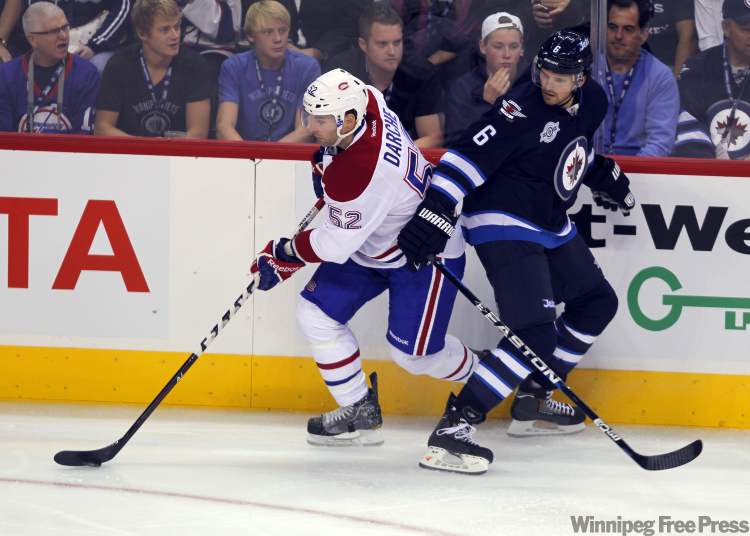 Canadien Mathieu Darche grabs the puck from Ron Hainsey during first-period action. (Boris Minkevich / Winnipeg Free Press)