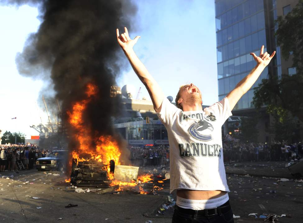 A Canucks fan yells and poses for a friends camera in front of a burning car as fans riot after the Vancouver Canucks lose to the Boston Bruins in The Stanley Cup final, Vancouver, British Columbia, Canada on Wednesday, June 15, 2011. (Gerry Kahrmann/PNG/Postmedia News)