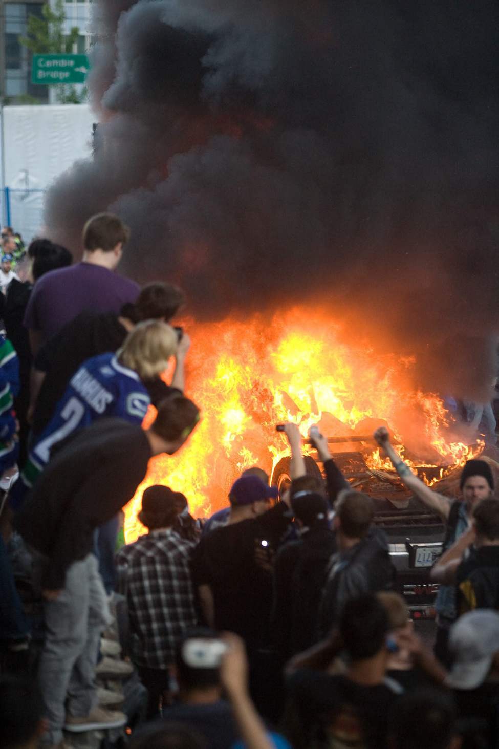 Vancouver Canucks fans watch a car burn during a riot following game 7 of the NHL Stanley Cup final in downtown Vancouver, B.C., on Wednesday, June 15, 2011. THE CANADIAN PRESS/Geoff Howe